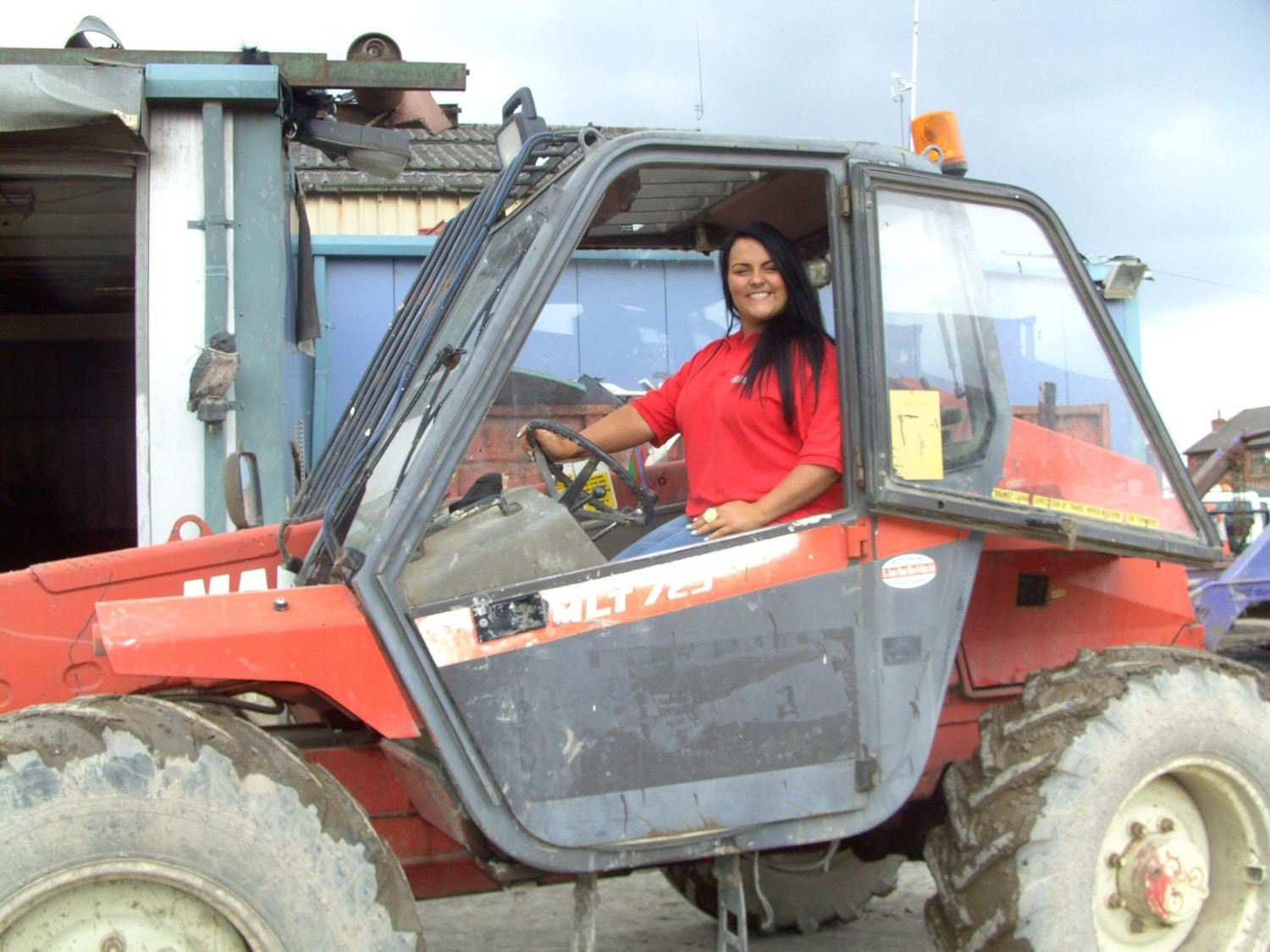 Woman in a digger smiling. subject is skip hire benefiting eco friendly business